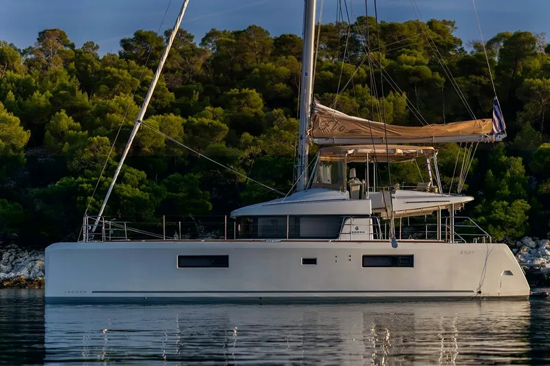  Yacht Photos Pics 2018 Lagoon 52 F catamaran anchored near lush green forest.