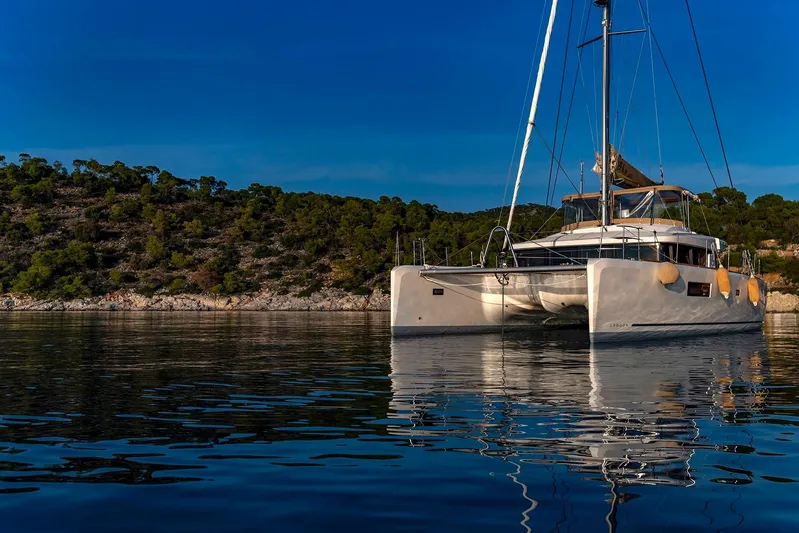 Yacht Photos Pics 2018 Lagoon 52 F catamaran anchored in serene waters, with lush green hills in the background.