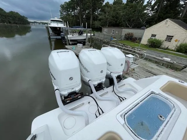  Yacht Photos Pics 2022 Invincible 36 Open Fisherman with triple outboard engines docked by a serene waterfront.