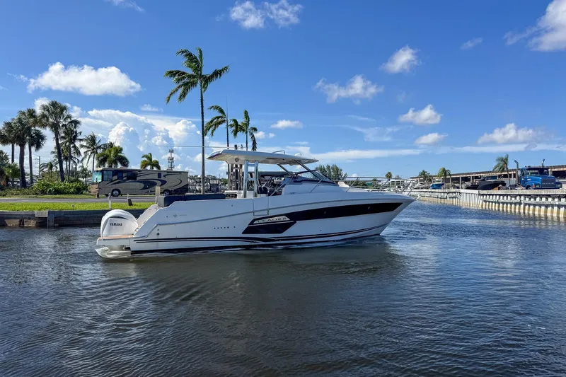 Trade In Yacht Photos Pics 2022 Jeanneau Leader 12.5 WA boat cruising on a sunny day with palm trees.