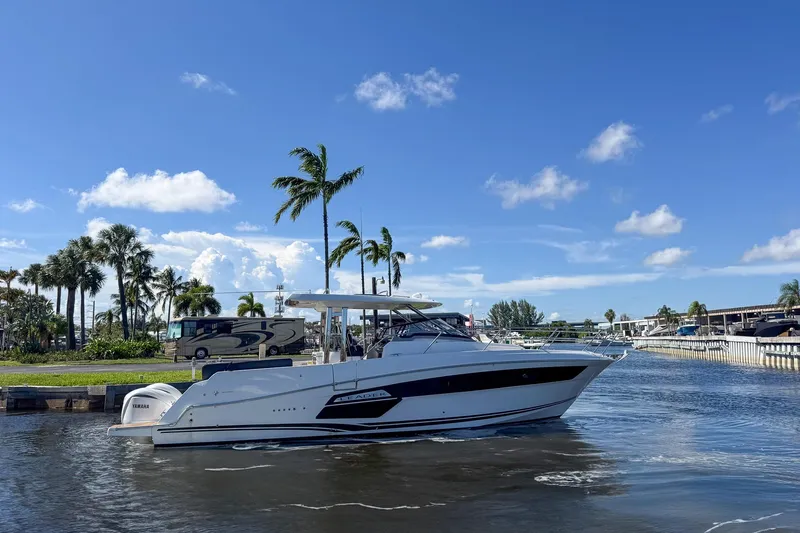 Trade In Yacht Photos Pics 2022 Jeanneau Leader 12.5 WA boat on a sunny day, surrounded by palm trees and water.