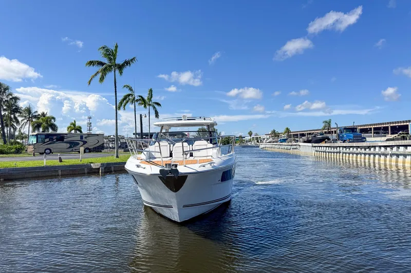 Trade In Yacht Photos Pics 2022 Jeanneau Leader 12.5 WA boat cruising on a sunny day with palm trees in the background.