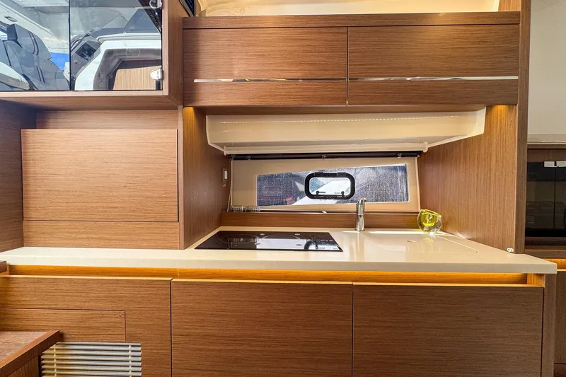 Trade In Yacht Photos Pics Modern kitchen interior on 2022 Jeanneau Leader 12.5 WA yacht, featuring sleek wood cabinetry.