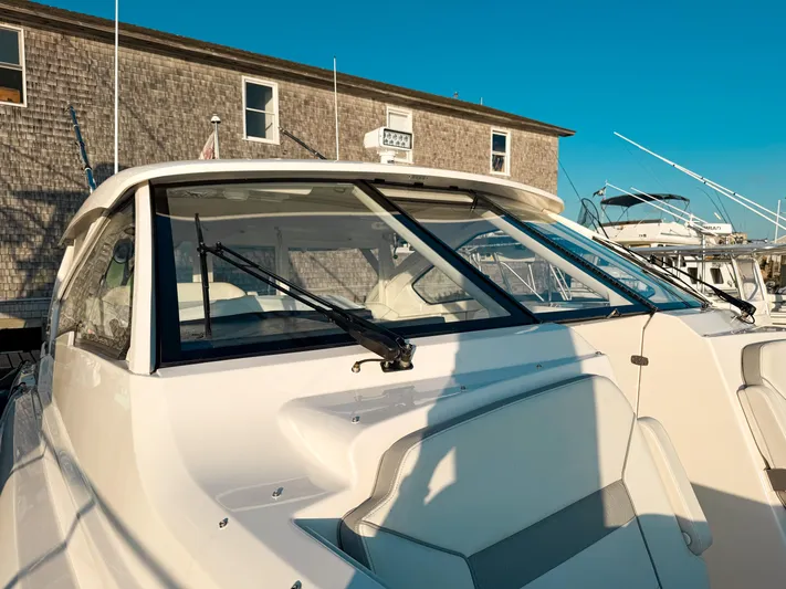  Yacht Photos Pics 2022 Pursuit DC 365 Dual Console boat docked near a wooden building under clear blue sky.