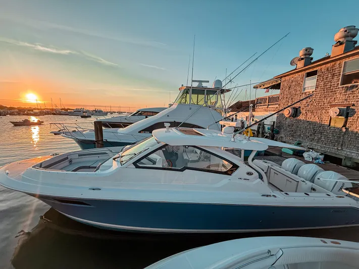  Yacht Photos Pics 2022 Pursuit DC 365 Dual Console boat docked at sunset, with serene water and clear sky.