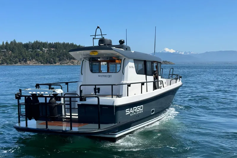 Sisu Yacht Photos Pics 2020 Sargo 31 boat cruising on a clear blue lake with mountains in the background.