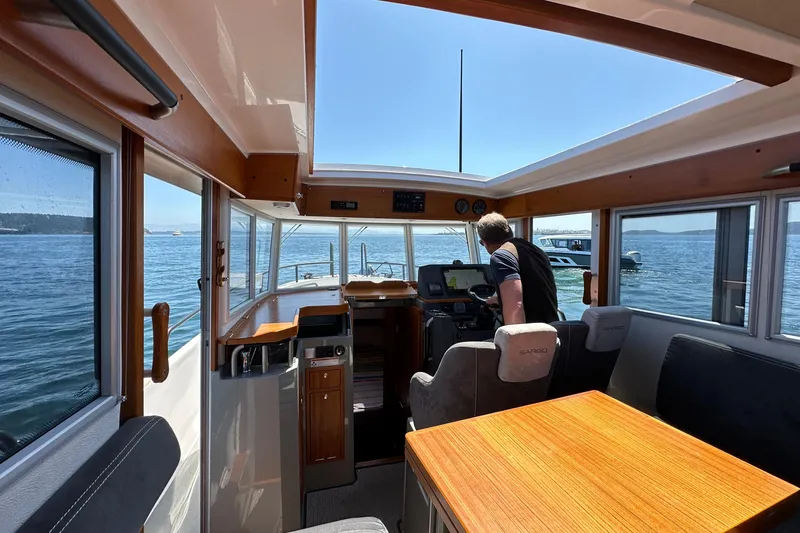 Sisu Yacht Photos Pics Interior of 2020 Sargo 31 boat with person at the helm, navigating on a sunny day.