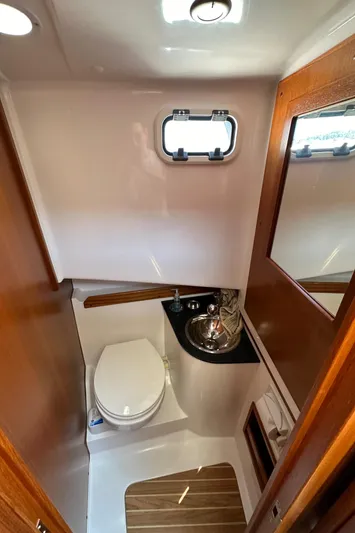Sisu Yacht Photos Pics Compact bathroom in 2020 Sargo 31 boat with toilet, sink, and wooden accents.