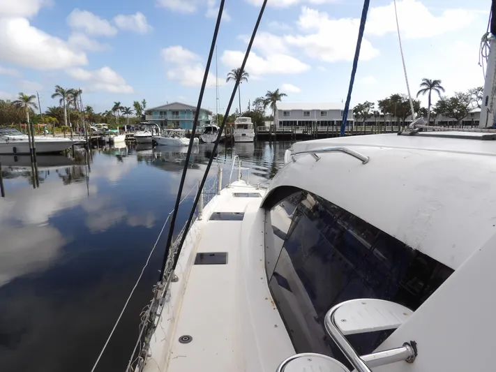  Yacht Photos Pics Leopard 48 yacht docked in a serene marina, surrounded by palm trees and calm waters.