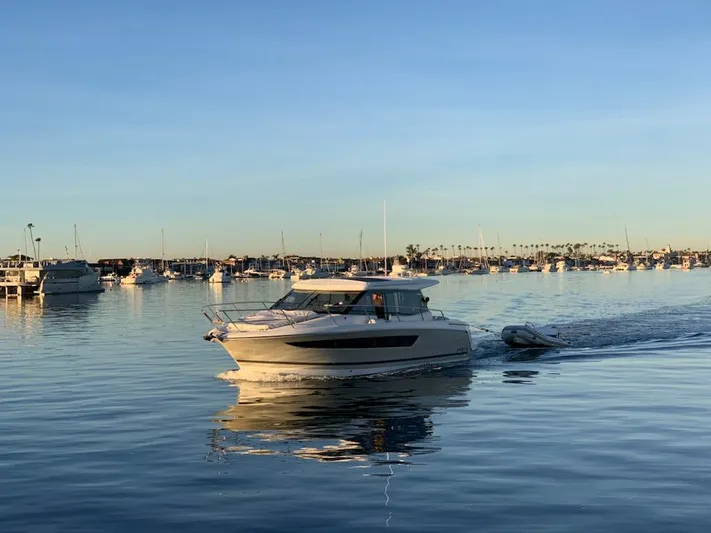 Dark Side Yacht Photos Pics 2017 Jeanneau NC11 cruising on calm waters at sunset, surrounded by anchored boats.