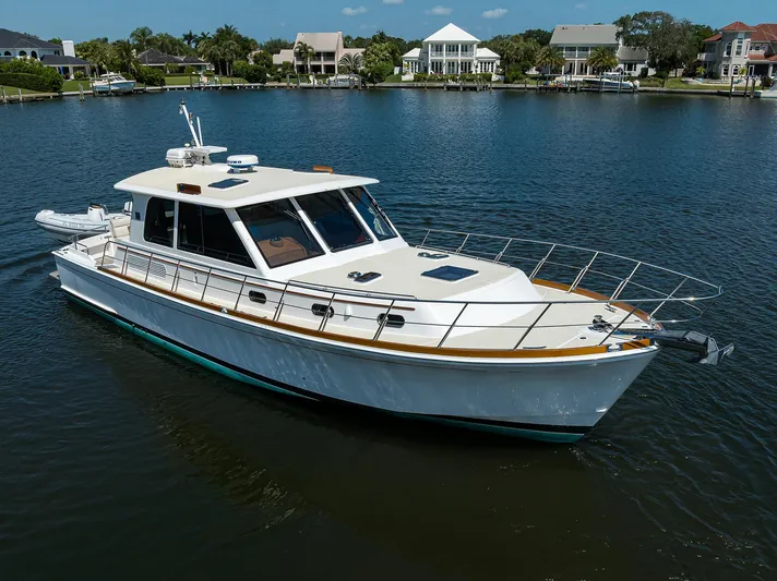 Seabird Yacht Photos Pics 2014 Grand Banks 46 Eastbay SX yacht on calm water near waterfront homes.