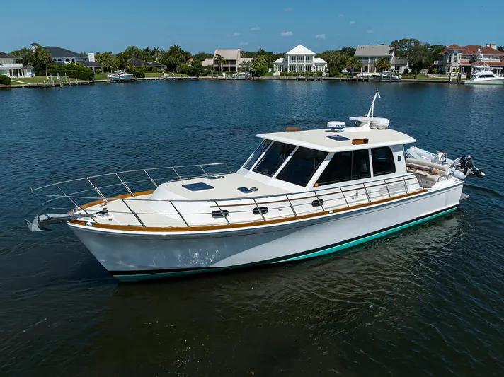Seabird Yacht Photos Pics 2014 Grand Banks 46 Eastbay SX yacht on calm water near waterfront homes.