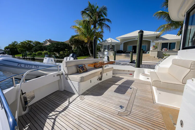 Seabird Yacht Photos Pics 2014 Grand Banks 46 Eastbay SX yacht deck with seating, docked near a waterfront home.