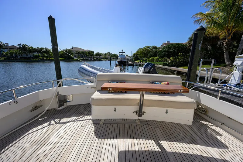 Seabird Yacht Photos Pics 2014 Grand Banks 46 Eastbay SX yacht deck with seating, docked by a scenic waterfront.