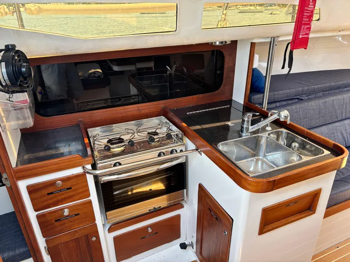 Ceilidh Yacht Photos Pics 2018 J Boats J/121 yacht interior kitchen with stove, sink, and wooden cabinetry.