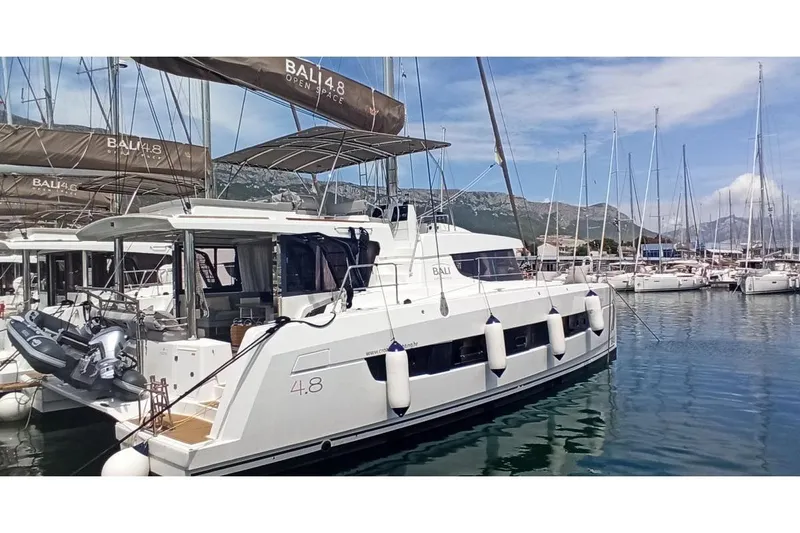 Tatani Yacht Photos Pics 2021 Bali 4.8 catamaran docked in a marina with scenic mountain backdrop.