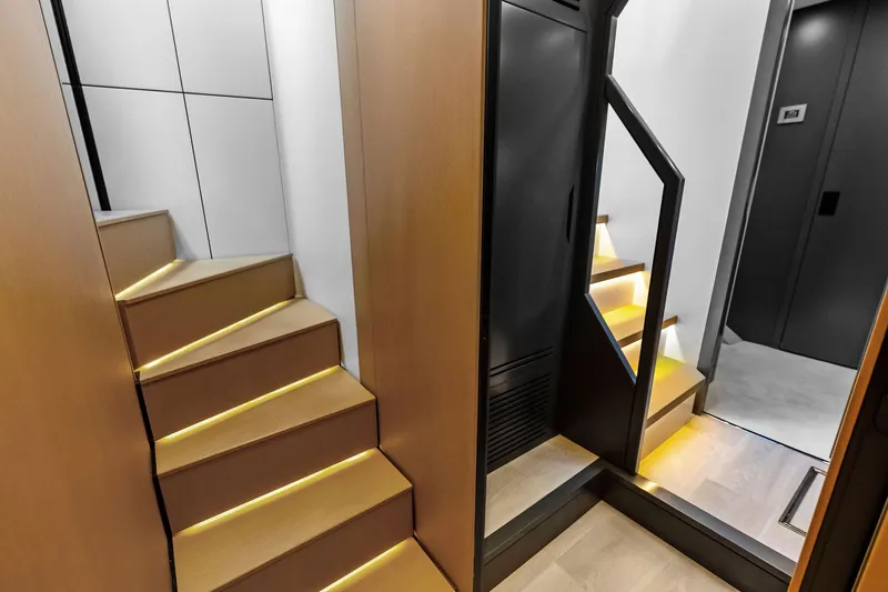 Another World Yacht Photos Pics Modern interior of 2025 Wally Wallytender 100 yacht with illuminated wooden stairs.