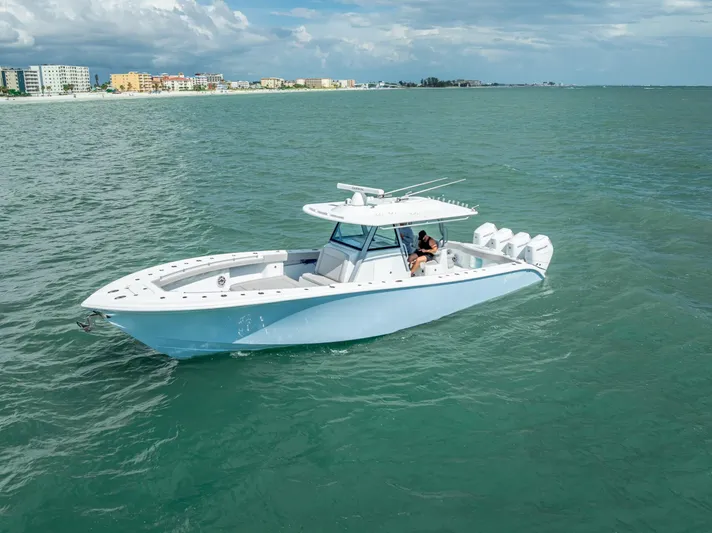  Yacht Photos Pics 2024 Yellowfin 39 boat cruising on calm ocean waters near a coastal city.