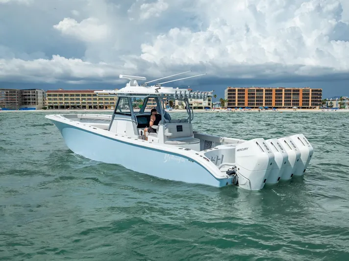  Yacht Photos Pics 2024 Yellowfin 39 boat on water with four engines, near coastal buildings under cloudy sky.