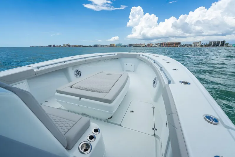  Yacht Photos Pics 2024 Yellowfin 39 boat interior with cushioned seating, ocean view, and city skyline in the background.