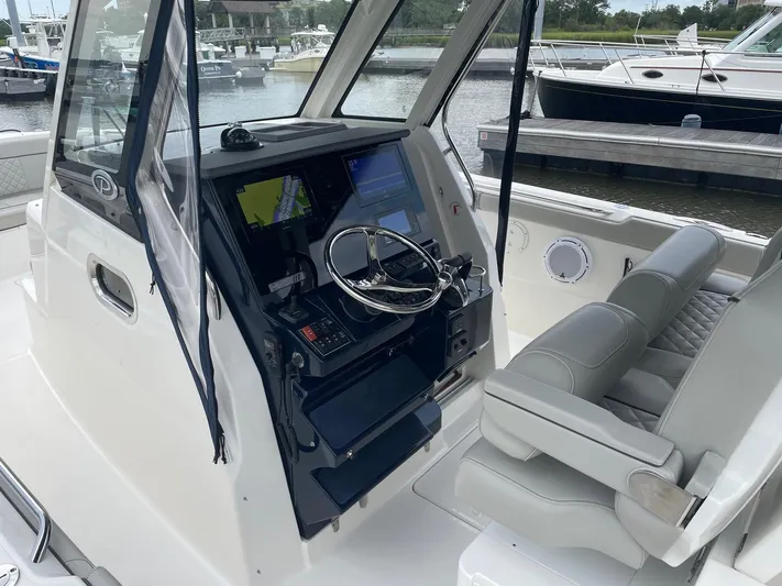  Yacht Photos Pics 2022 Pursuit S 328 Sport boat cockpit with navigation controls and seating.
