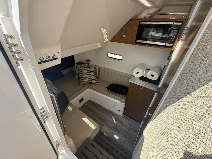  Yacht Photos Pics 2023 Everglades 395 Center Console cabin interior with seating, microwave, and storage.