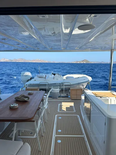 Yacht Photos Pics 2023 Lagoon 55 yacht deck with ocean view, featuring dining area and tender.