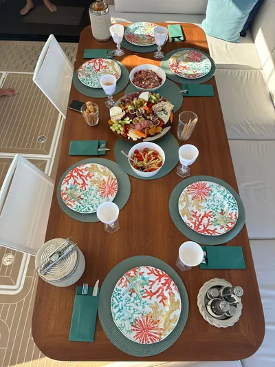  Yacht Photos Pics Elegant dining setup on Lagoon 55 yacht, featuring colorful plates and a variety of dishes.