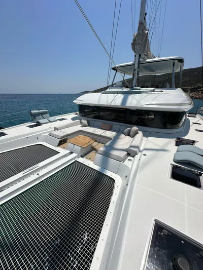  Yacht Photos Pics 2023 Lagoon 55 yacht deck with seating and netting, sailing on clear blue water.
