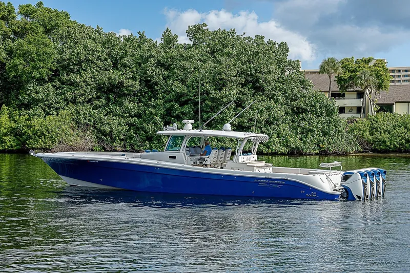  Yacht Photos Pics 2016 HCB 53 Sueños boat with blue hull cruising on a calm waterway.
