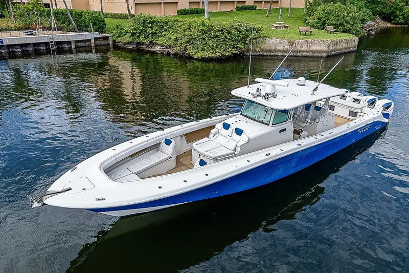  Yacht Photos Pics HCB 53 Sueños 2016 boat with blue hull, docked in calm waters, surrounded by greenery.
