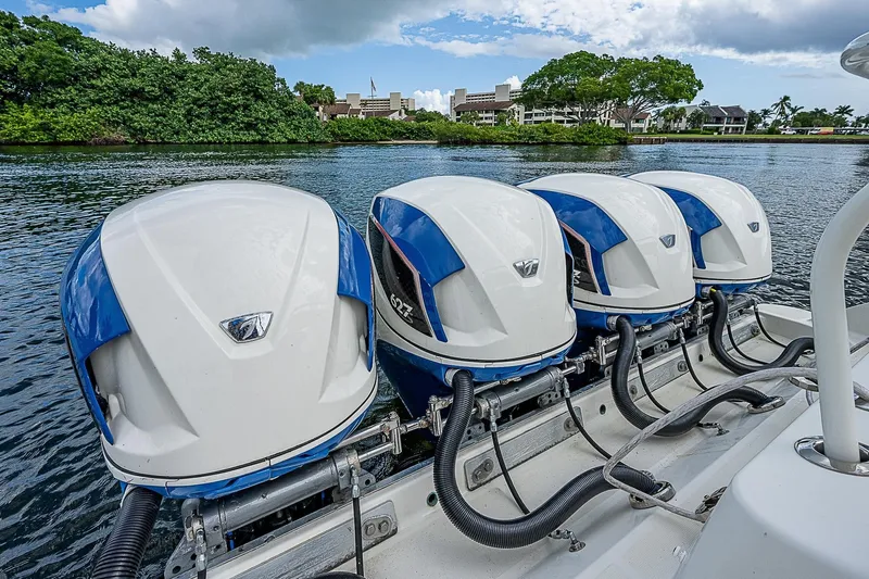  Yacht Photos Pics Four powerful outboard engines on a 2016 HCB 53 Sueños boat, docked by lush greenery.