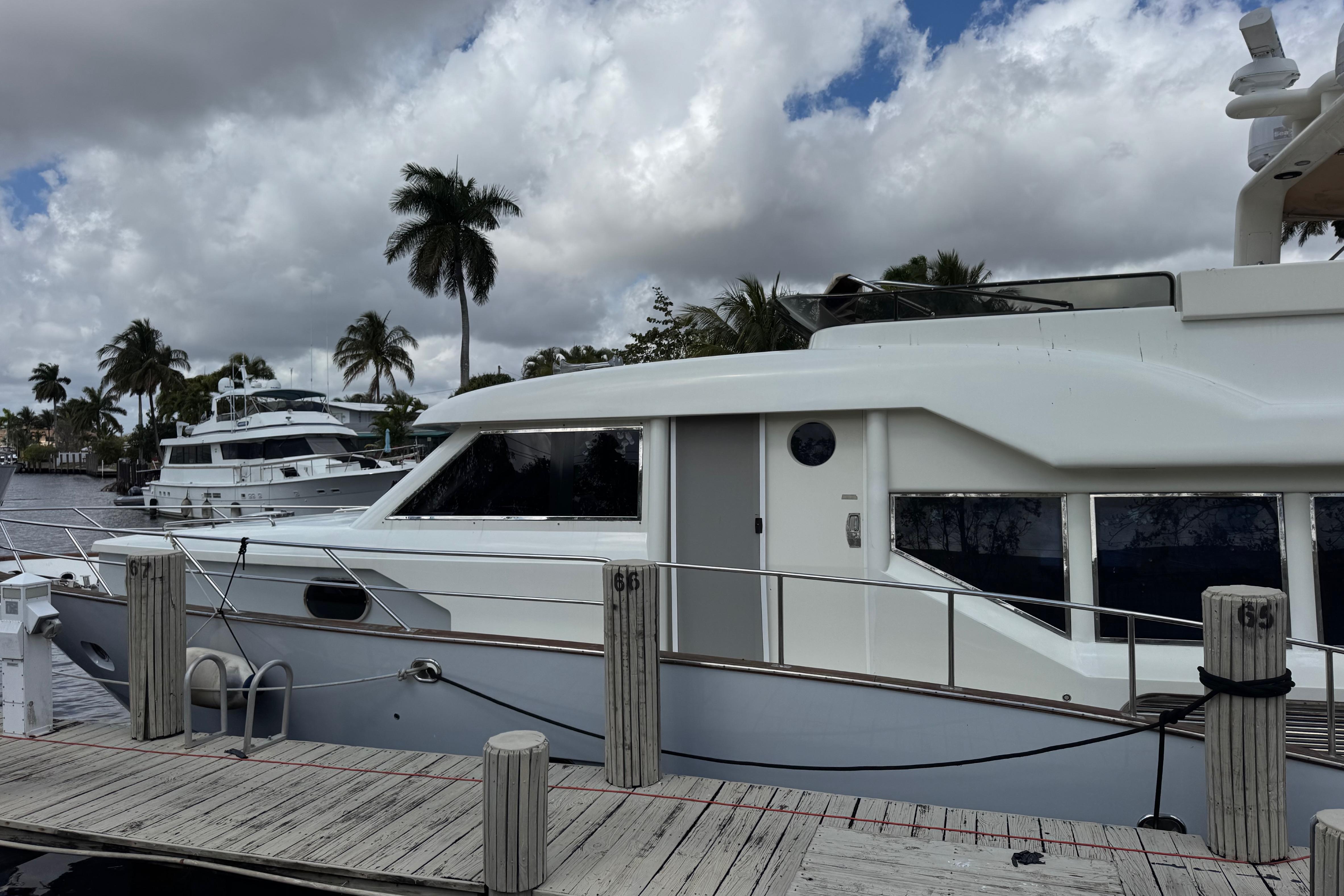 2003 Custom Sea Star Pilot House yacht docked, with palm trees and cloudy sky in the background.
