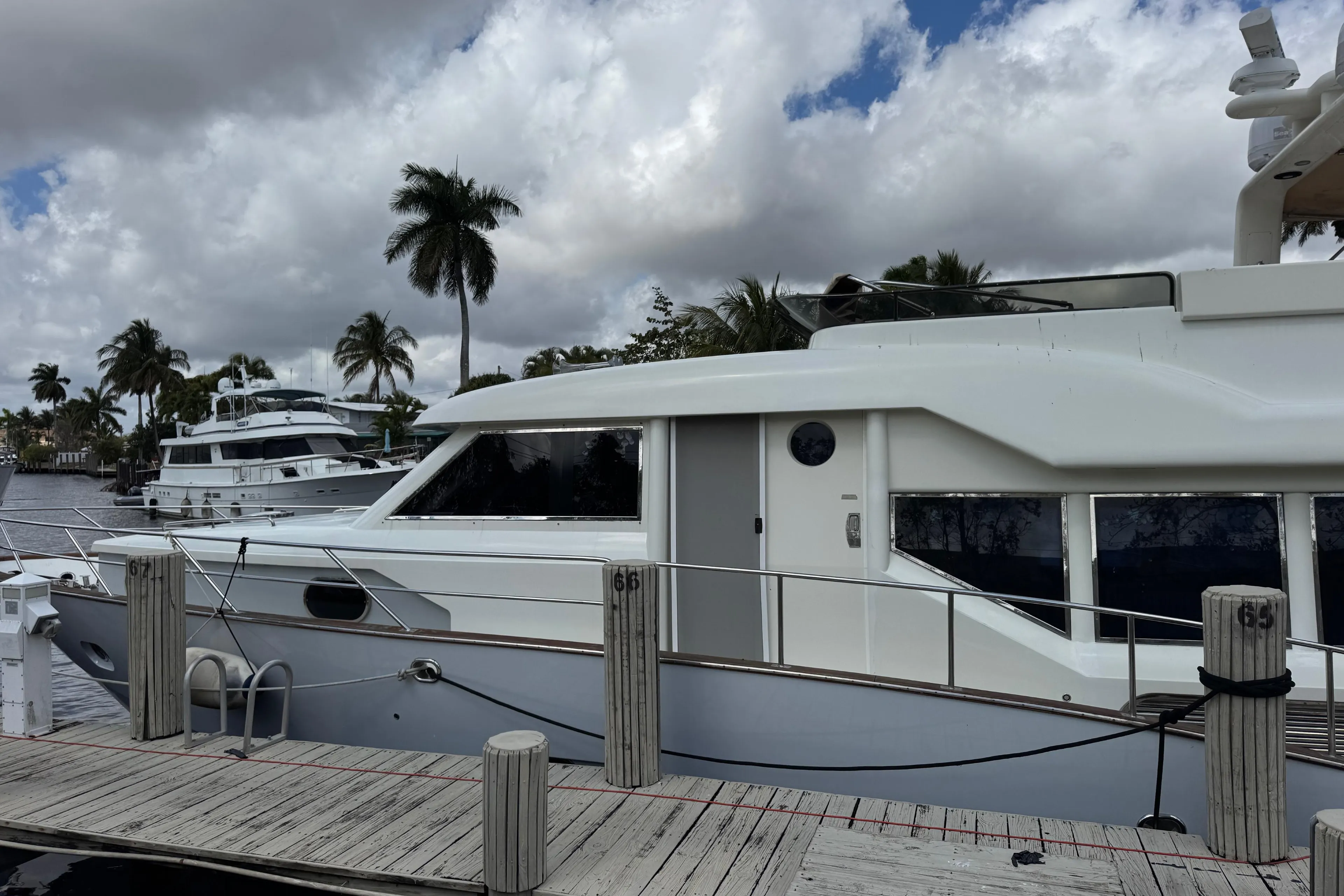 2003 Custom Sea Star Pilot House yacht docked, with palm trees and cloudy sky in the background.