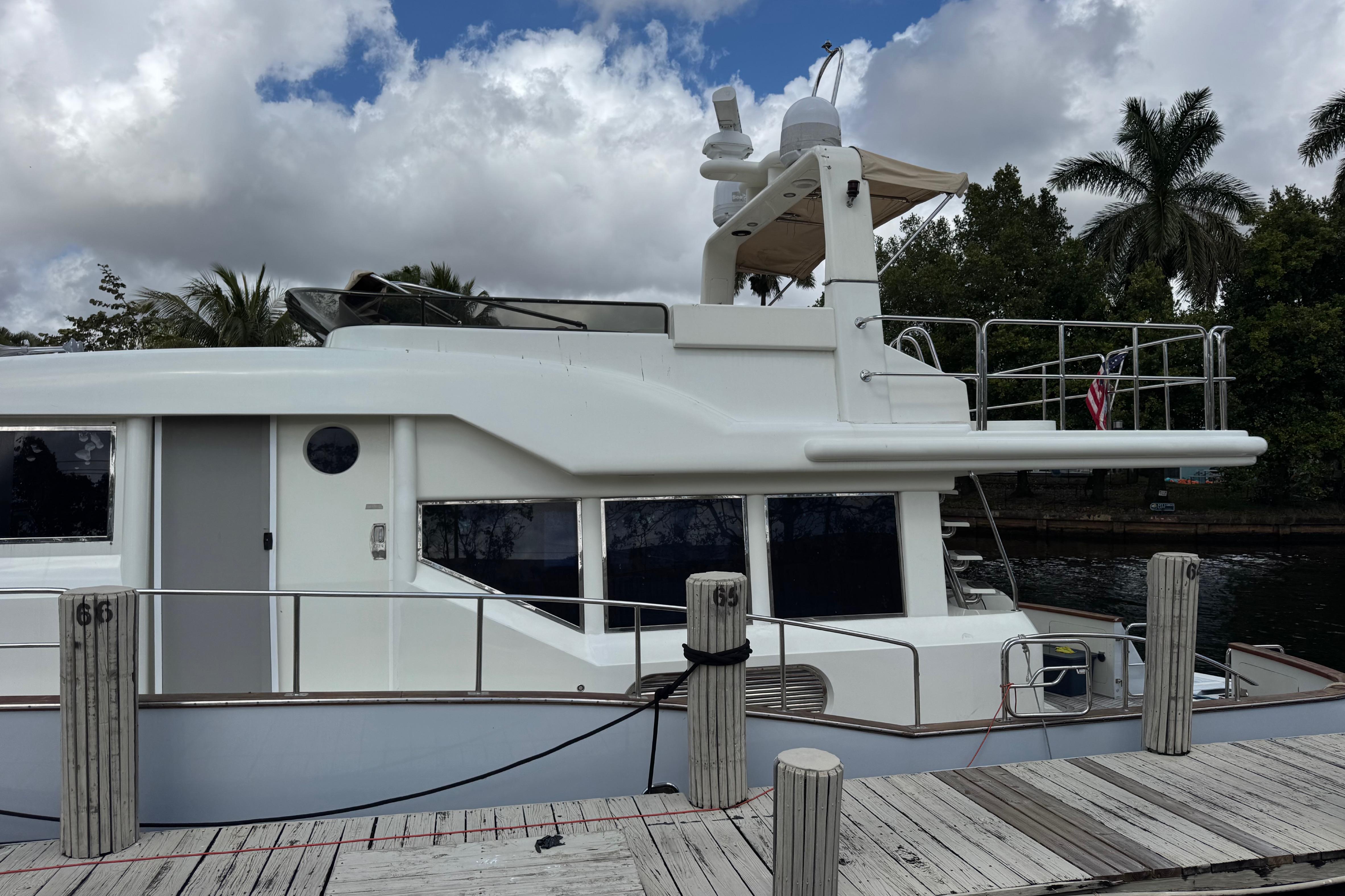 Custom 2003 Sea Star Pilot House yacht docked, with palm trees and cloudy sky in the background.