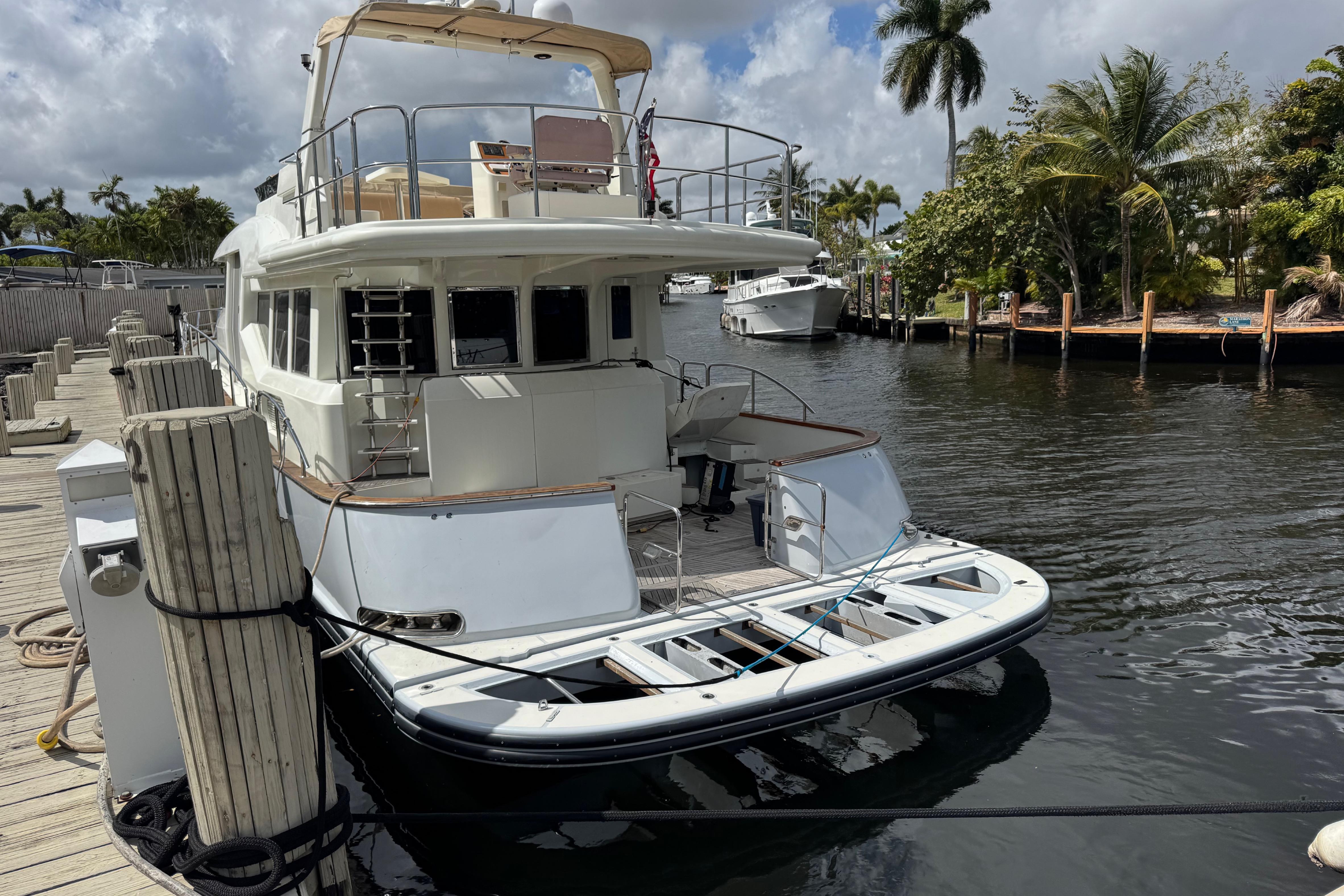 2003 Custom Sea Star Pilot House yacht docked by palm trees and calm water.