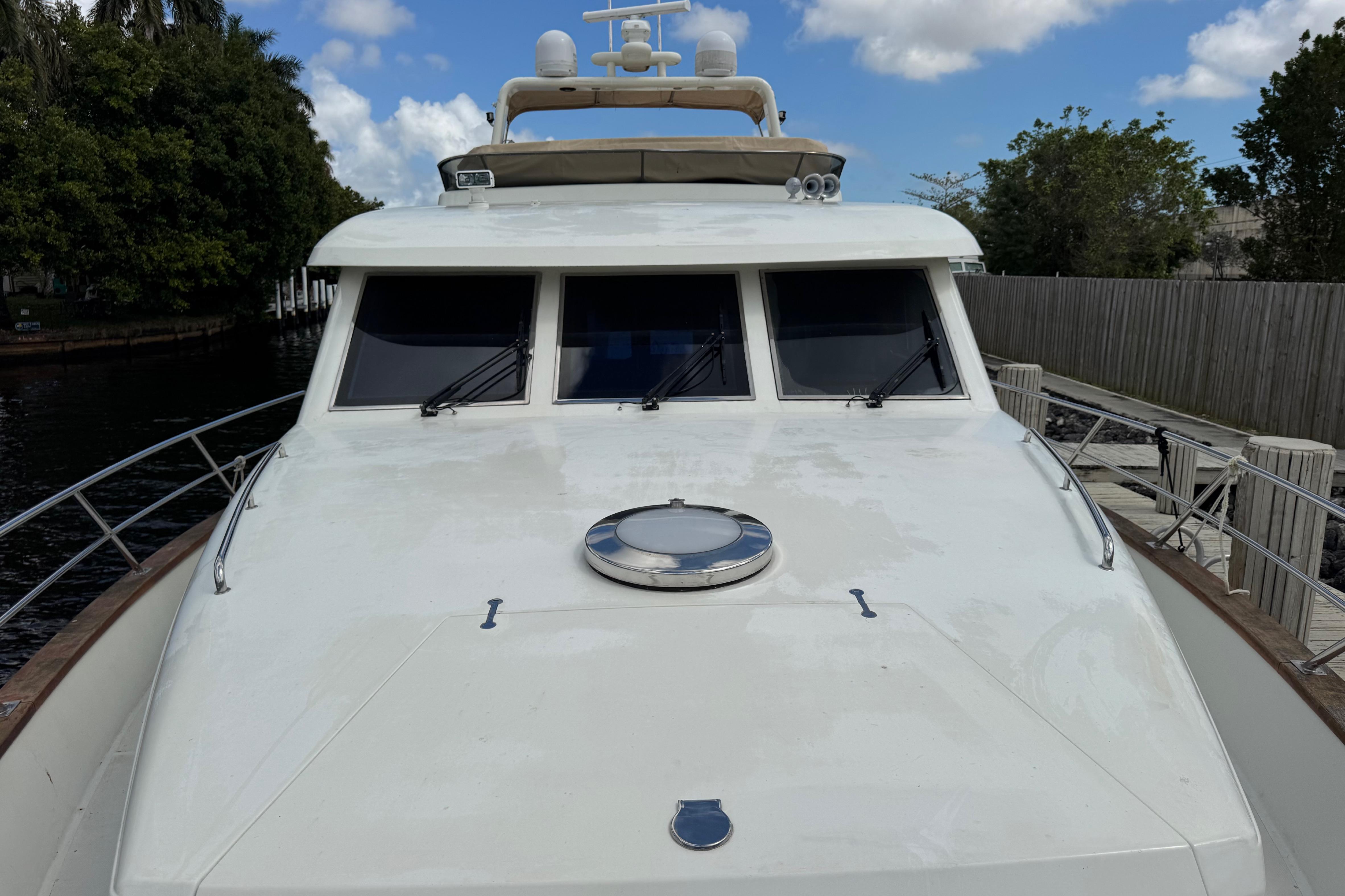 Front view of 2003 Custom Sea Star Pilot House boat docked by a wooden fence.