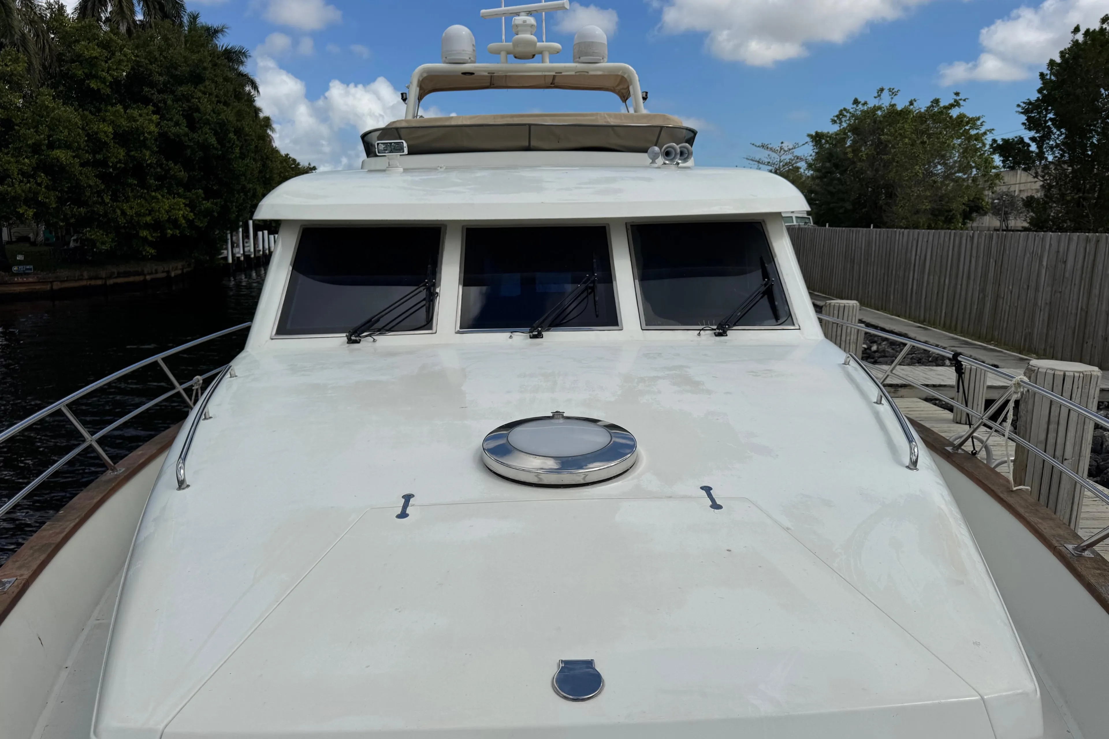 Front view of 2003 Custom Sea Star Pilot House boat docked by a wooden fence.