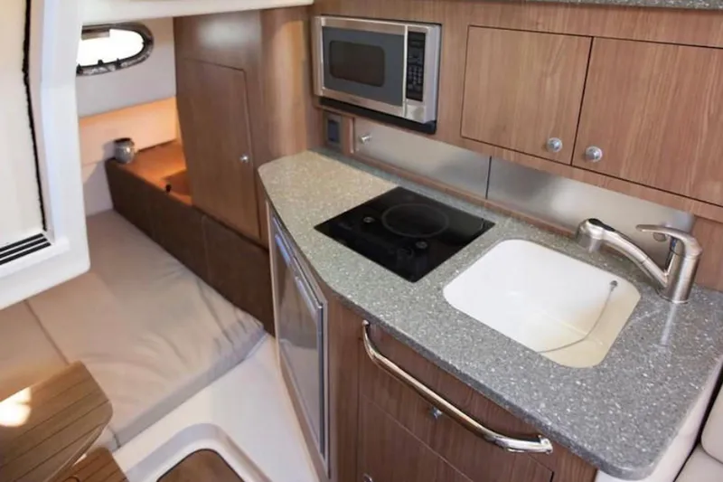 Outta Line Yacht Photos Pics 2017 Boston Whaler 315 Conquest interior with kitchenette, featuring sink, stove, and microwave.