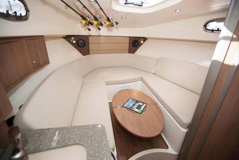 Outta Line Yacht Photos Pics 2017 Boston Whaler 315 Conquest cabin interior with beige seating and wooden table.