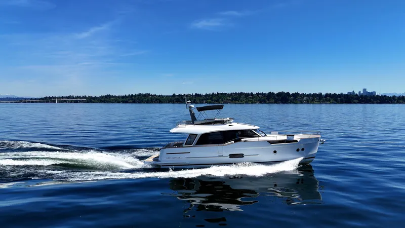  Yacht Photos Pics 2024 Greenline 48 Fly yacht cruising on a calm lake under a clear blue sky.