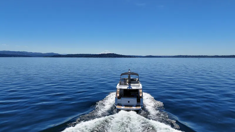  Yacht Photos Pics 2024 Greenline 48 Fly yacht cruising on a calm, blue lake under a clear sky.