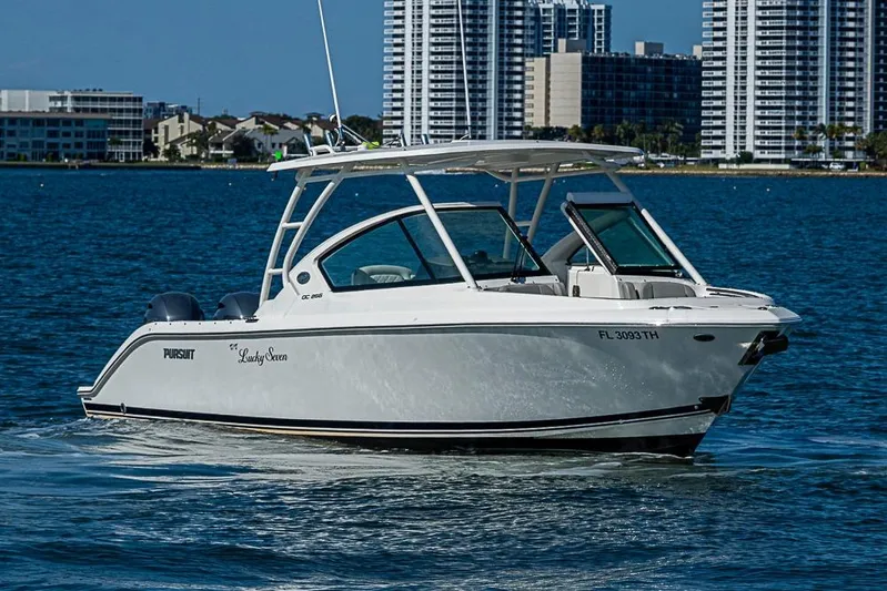 T/t Lucky Seven Yacht Photos Pics 2022 Pursuit DC 266 Dual Console boat cruising on water with city skyline backdrop.