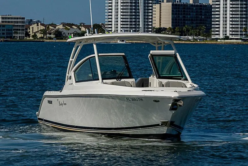 T/t Lucky Seven Yacht Photos Pics 2022 Pursuit DC 266 Dual Console boat cruising on water near city skyline.