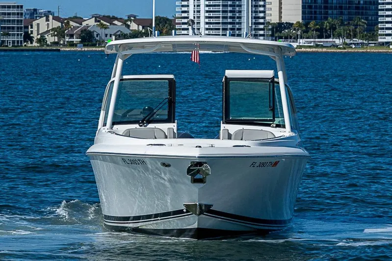 T/t Lucky Seven Yacht Photos Pics 2022 Pursuit DC 266 Dual Console boat cruising on blue water near cityscape.