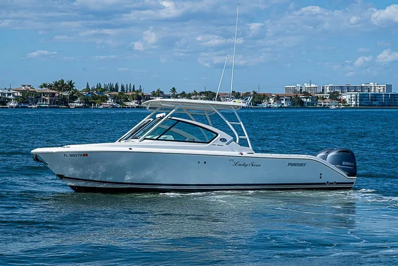 T/t Lucky Seven Yacht Photos Pics 2022 Pursuit DC 266 Dual Console boat cruising on a sunny day near coastal buildings.