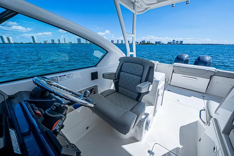 T/t Lucky Seven Yacht Photos Pics 2022 Pursuit DC 266 Dual Console boat interior with steering wheel, luxurious seating, and ocean view.