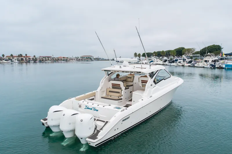  Yacht Photos Pics 2018 Pursuit boat on calm water, featuring triple outboard engines, docked in a marina.