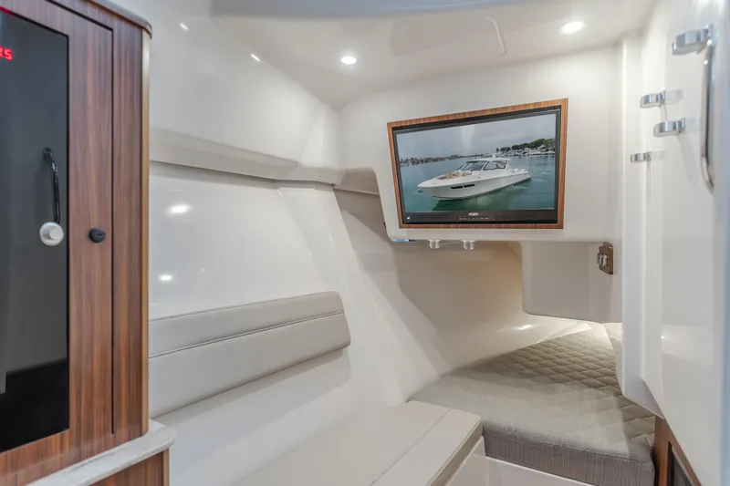  Yacht Photos Pics 2018 Pursuit boat interior with TV, cushioned seating, and wood accents.