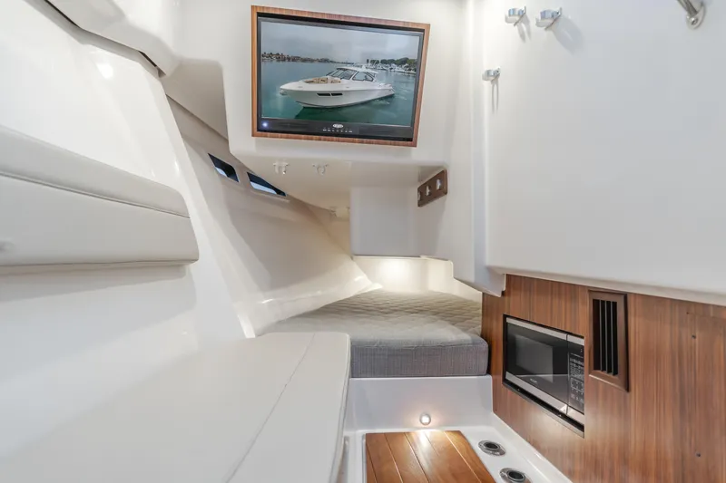  Yacht Photos Pics Luxurious 2018 Pursuit boat interior with bed, microwave, and framed boat picture.